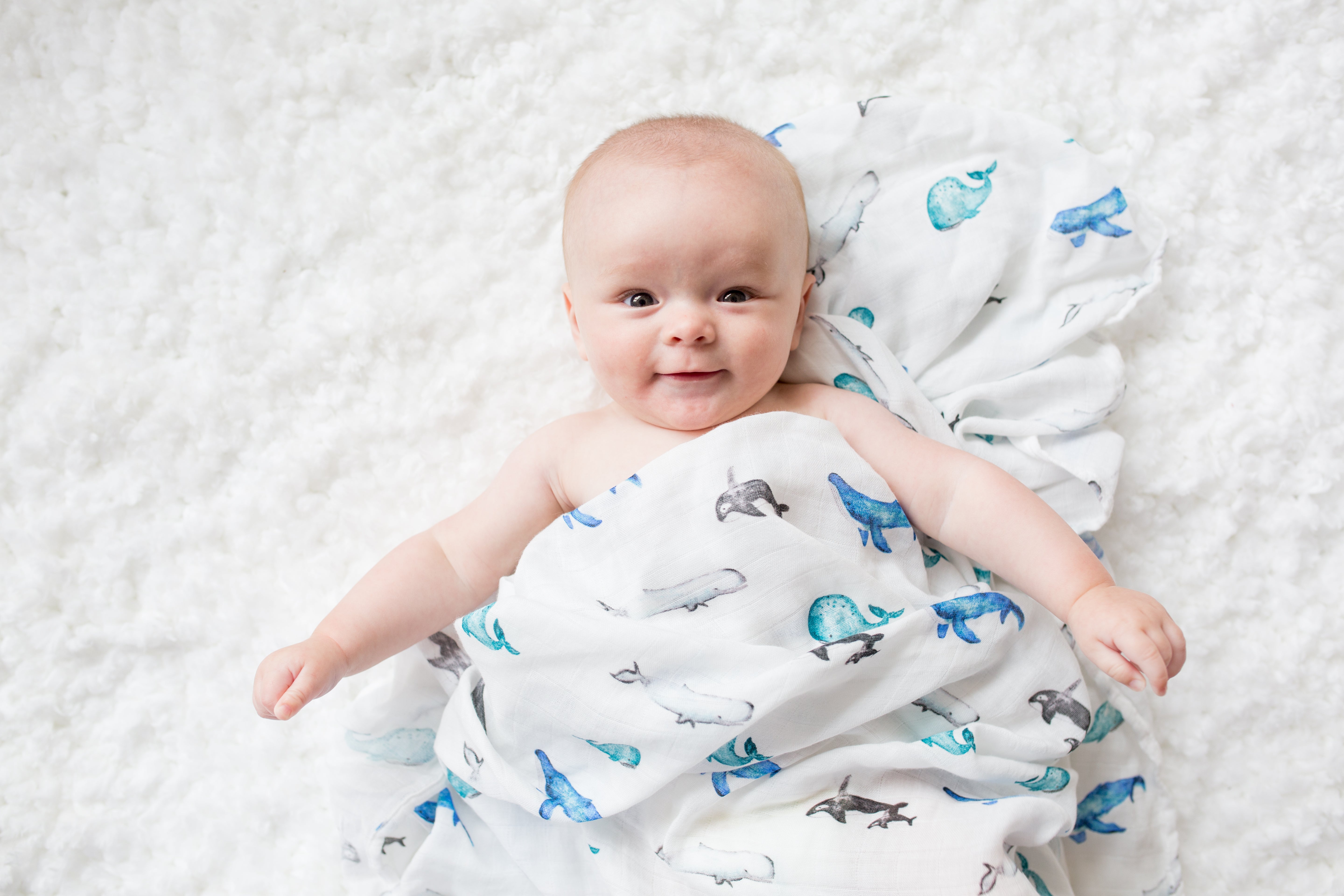 Baby wrapped in a blanket with dinosaur pattern