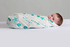 Baby swaddled in a white muslin blanket with turquoise blue sea shells and starfish ocean pattern